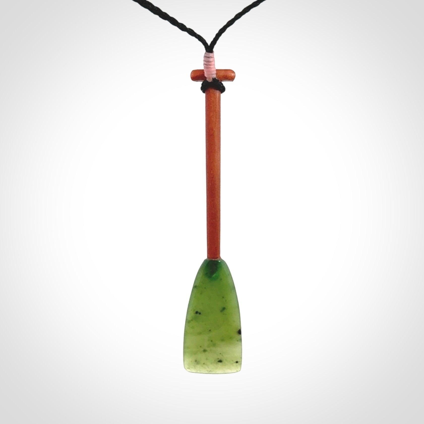 This pendant is a hand carved dragon boat paddle. We have carved this with a Green Nephrite jade blade and a hardwood handle. It is a necklace that was carved for suffered of breast cancer who are members of the Pink Dragons, a group or cancer fighters who take part in Dragon Boat racing events around the world.