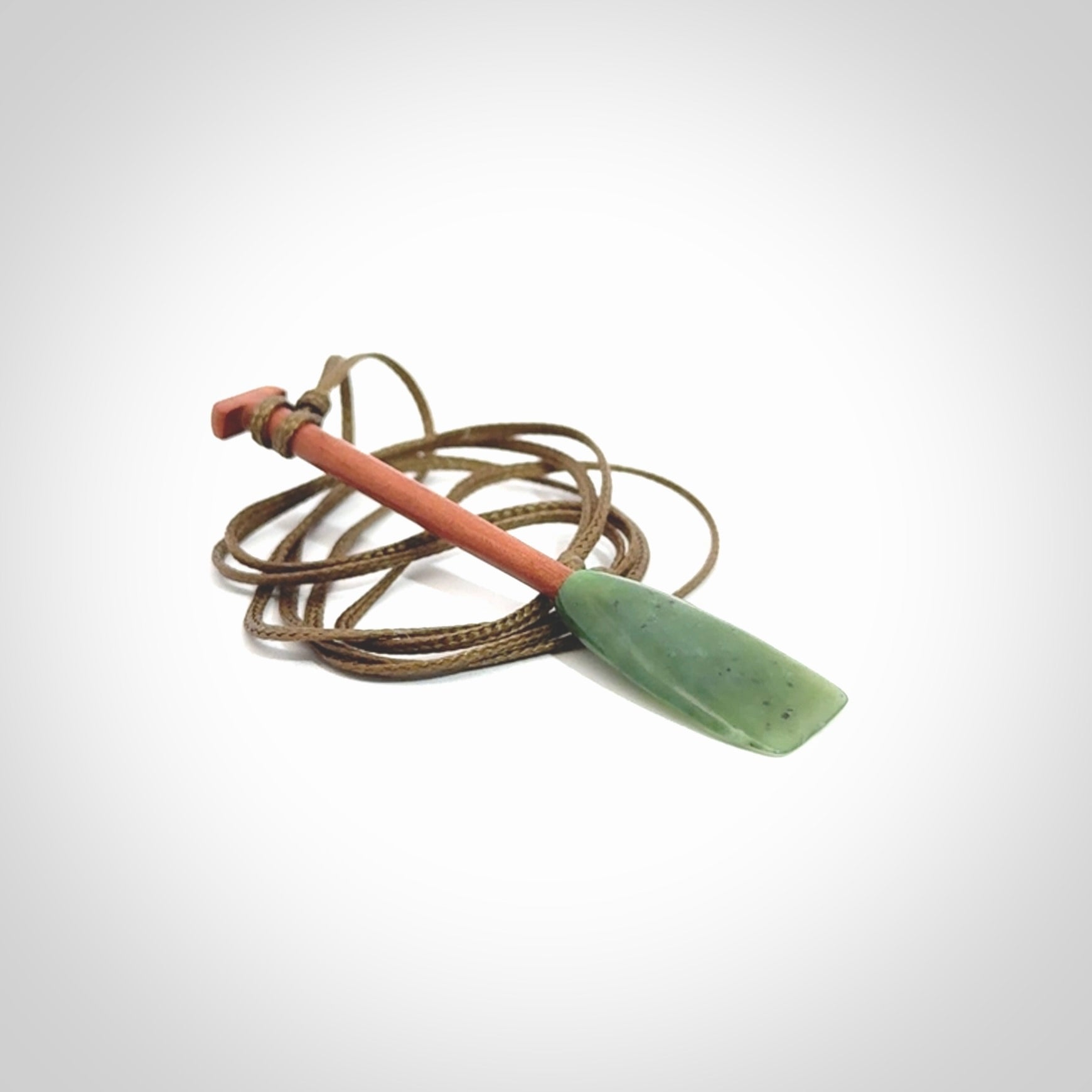 This pendant is a hand carved dragon boat paddle. We have carved this with a Green Nephrite jade blade and a hardwood handle. It is a necklace that was carved for suffered of breast cancer who are members of the Pink Dragons, a group or cancer fighters who take part in Dragon Boat racing events around the world.