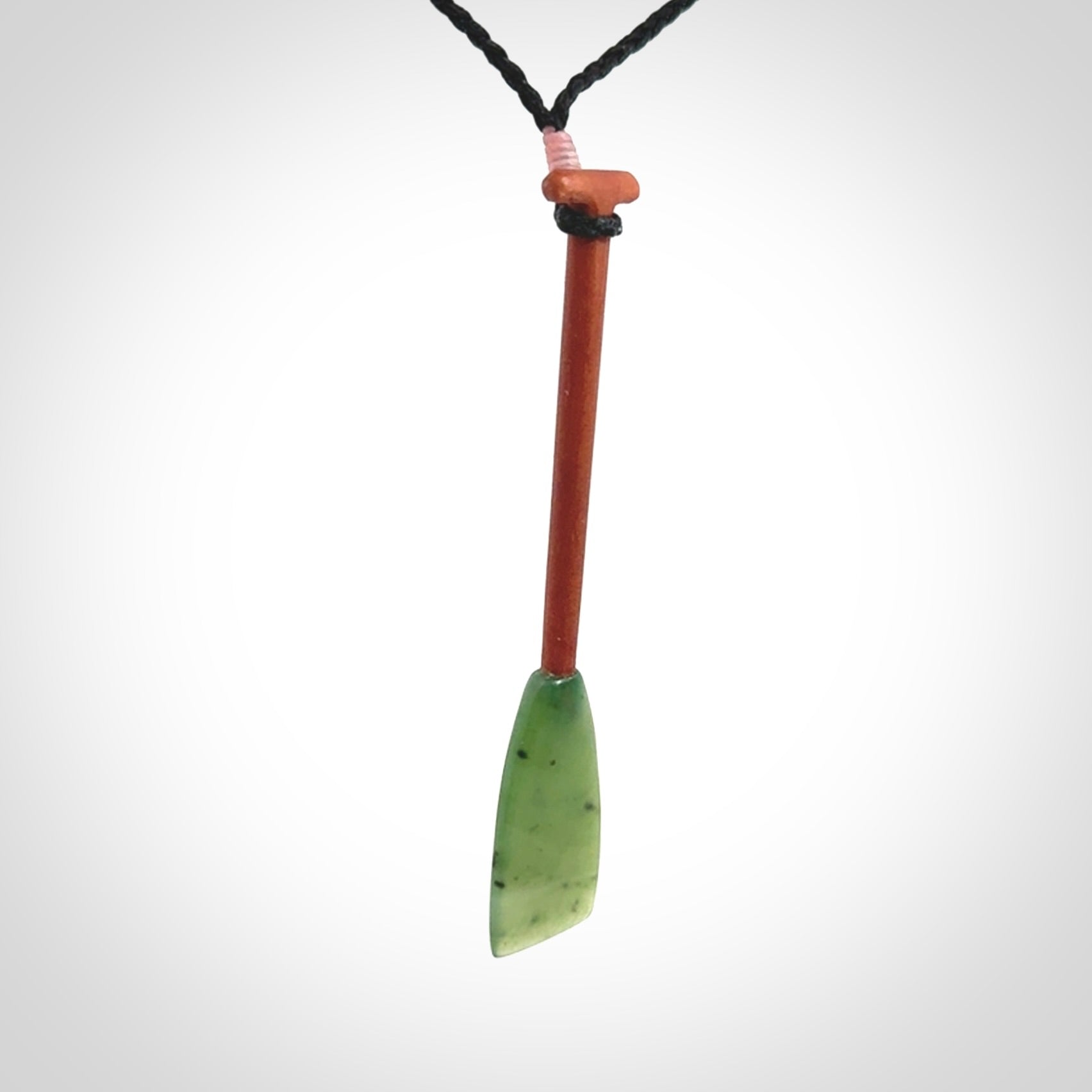 This pendant is a hand carved dragon boat paddle. We have carved this with a Green Nephrite jade blade and a hardwood handle. It is a necklace that was carved for suffered of breast cancer who are members of the Pink Dragons, a group or cancer fighters who take part in Dragon Boat racing events around the world.