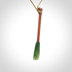 This pendant is a hand carved dragon boat paddle. We have carved this with a Green Nephrite jade blade and a hardwood handle. It is a necklace that was carved for suffered of breast cancer who are members of the Pink Dragons, a group or cancer fighters who take part in Dragon Boat racing events around the world.