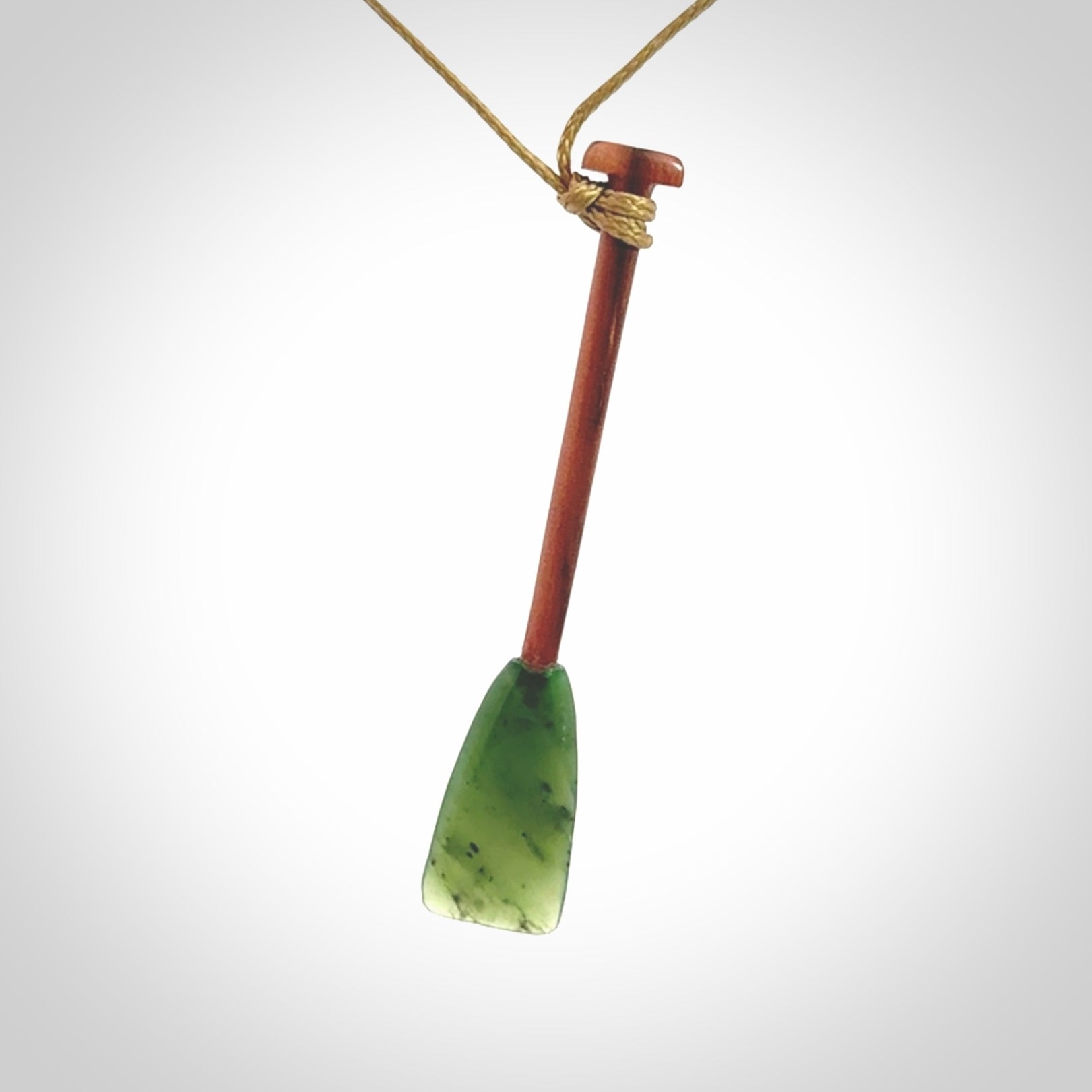 This pendant is a hand carved dragon boat paddle. We have carved this with a Green Nephrite jade blade and a hardwood handle. It is a necklace that was carved for suffered of breast cancer who are members of the Pink Dragons, a group or cancer fighters who take part in Dragon Boat racing events around the world.