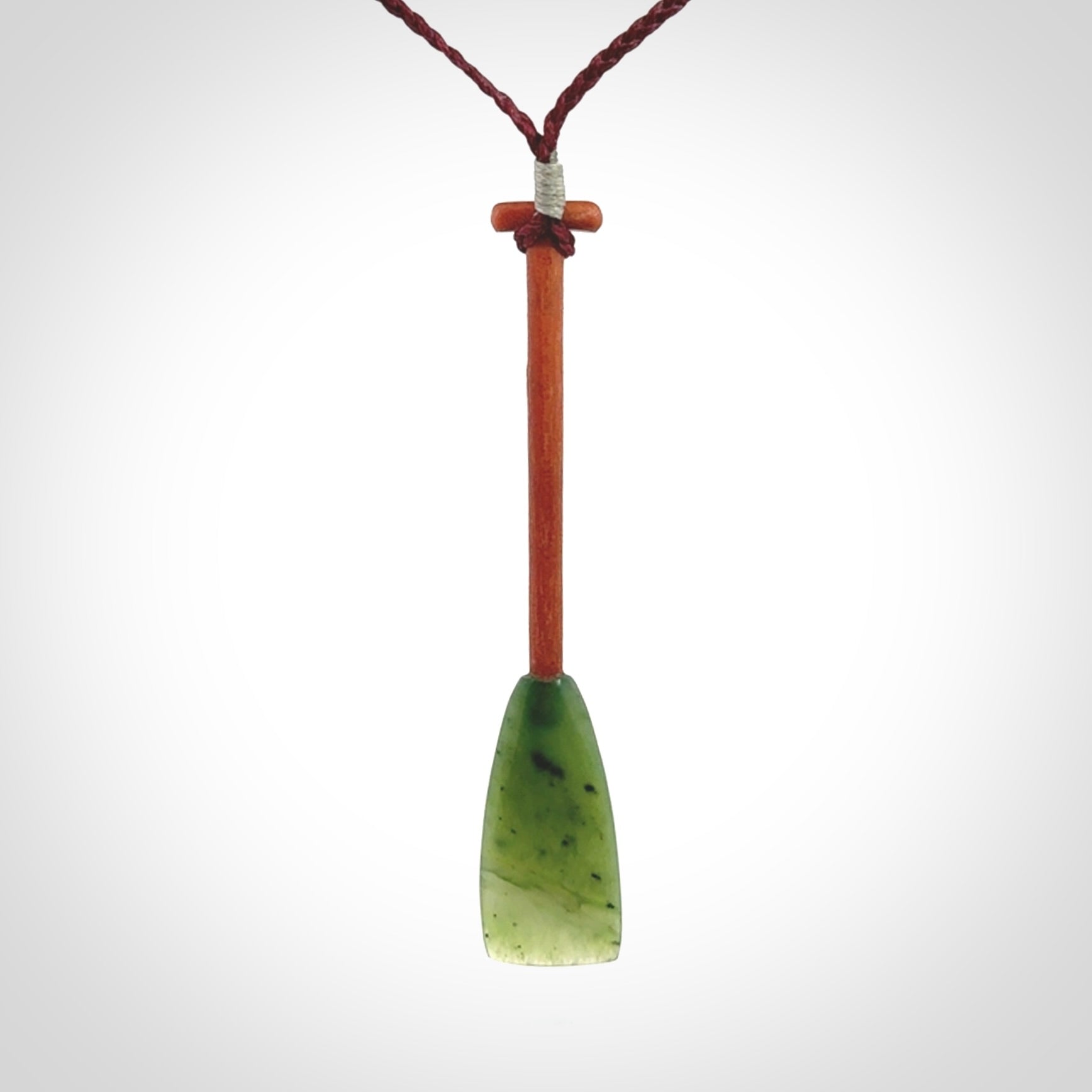 This pendant is a hand carved dragon boat paddle. We have carved this with a Green Nephrite jade blade and a hardwood handle. It is a necklace that was carved for suffered of breast cancer who are members of the Pink Dragons, a group or cancer fighters who take part in Dragon Boat racing events around the world.