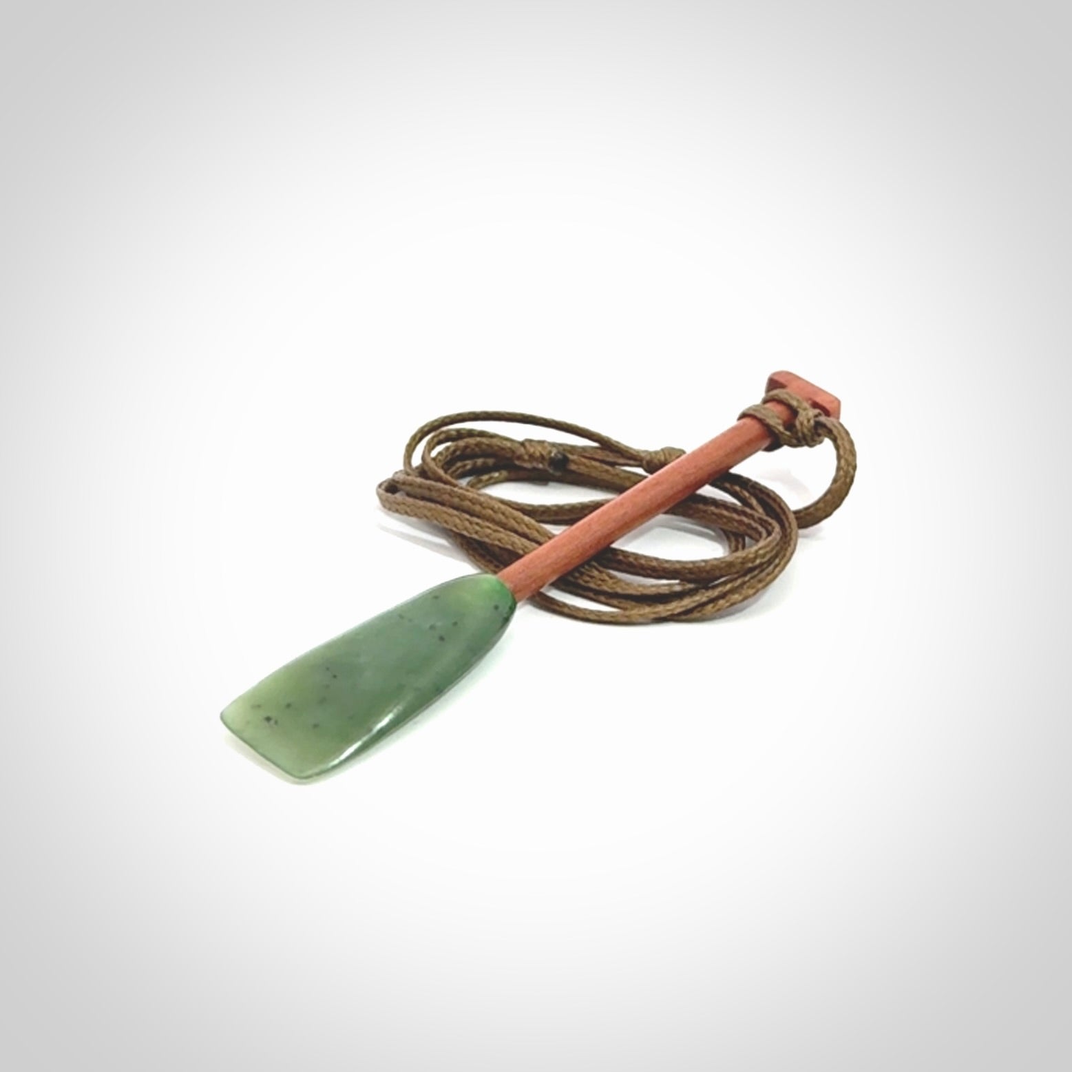 This pendant is a hand carved dragon boat paddle. We have carved this with a Green Nephrite jade blade and a hardwood handle. It is a necklace that was carved for suffered of breast cancer who are members of the Pink Dragons, a group or cancer fighters who take part in Dragon Boat racing events around the world.