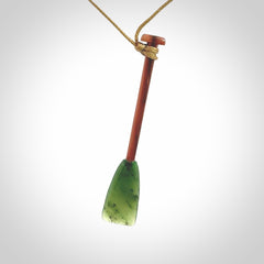 This pendant is a hand carved dragon boat paddle. We have carved this with a Green Nephrite jade blade and a hardwood handle. It is a necklace that was carved for suffered of breast cancer who are members of the Pink Dragons, a group or cancer fighters who take part in Dragon Boat racing events around the world.