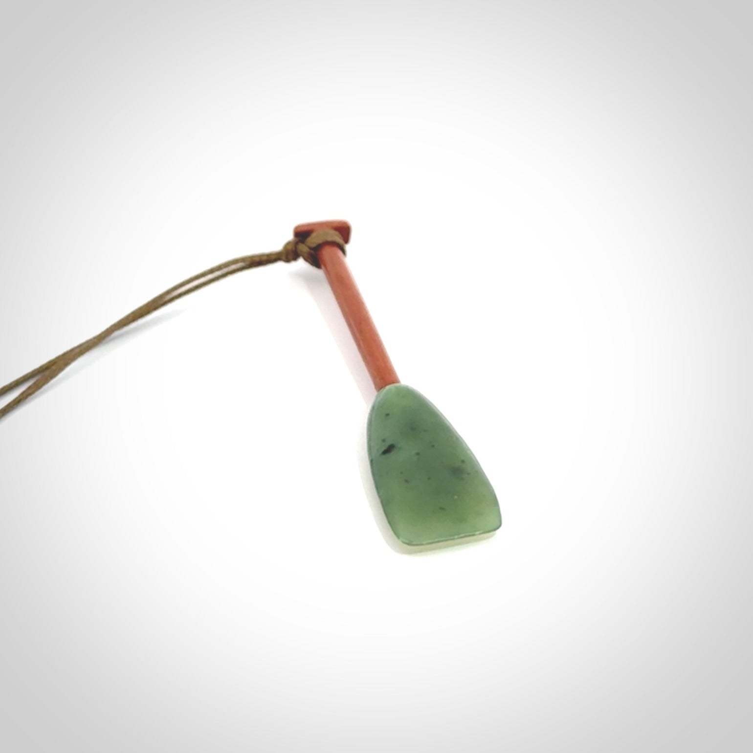 This pendant is a hand carved dragon boat paddle. We have carved this with a Green Nephrite jade blade and a hardwood handle. It is a necklace that was carved for suffered of breast cancer who are members of the Pink Dragons, a group or cancer fighters who take part in Dragon Boat racing events around the world.