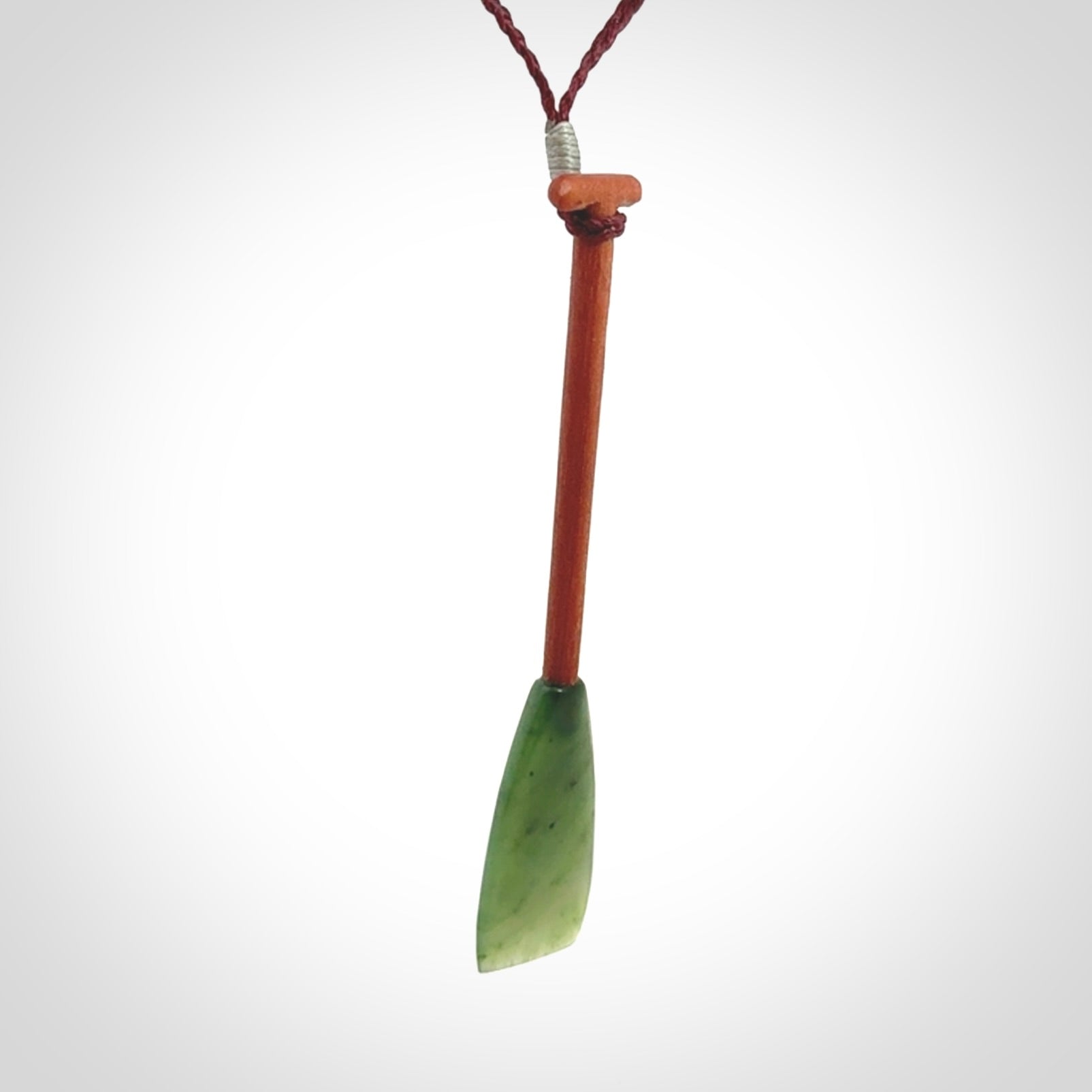 This pendant is a hand carved dragon boat paddle. We have carved this with a Green Nephrite jade blade and a hardwood handle. It is a necklace that was carved for suffered of breast cancer who are members of the Pink Dragons, a group or cancer fighters who take part in Dragon Boat racing events around the world.