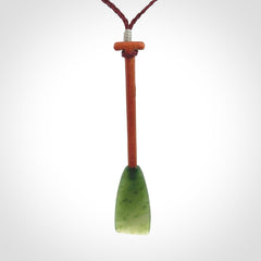 This pendant is a hand carved dragon boat paddle. We have carved this with a Green Nephrite jade blade and a hardwood handle. It is a necklace that was carved for suffered of breast cancer who are members of the Pink Dragons, a group or cancer fighters who take part in Dragon Boat racing events around the world.