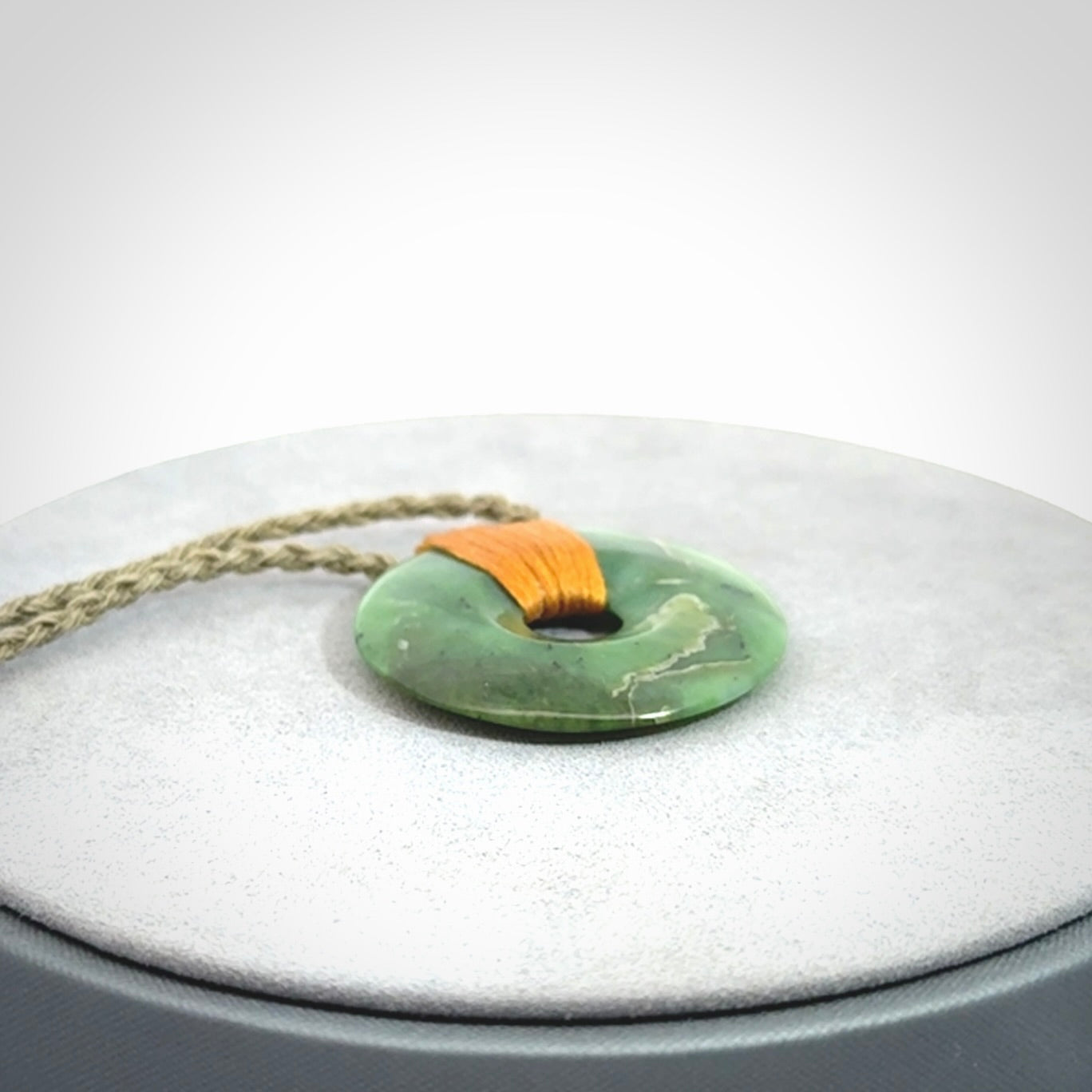 This is a hand carved disc pendant. Graeme carved this from Nephrite Jade. It is a gorgeous green colour and is an artistic piece of jewellery. Hand made by Graeme Wylie and delivered to you in a kete pouch.