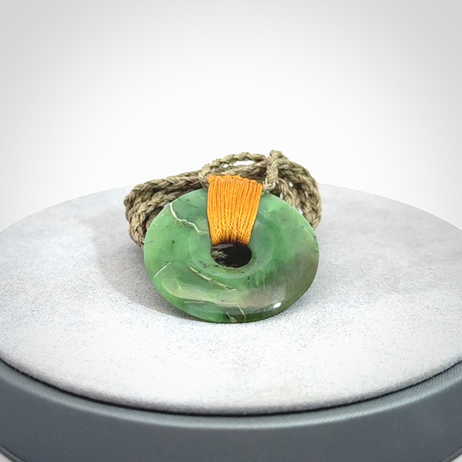 This is a hand carved disc pendant. Graeme carved this from Nephrite Jade. It is a gorgeous green colour and is an artistic piece of jewellery. Hand made by Graeme Wylie and delivered to you in a kete pouch.