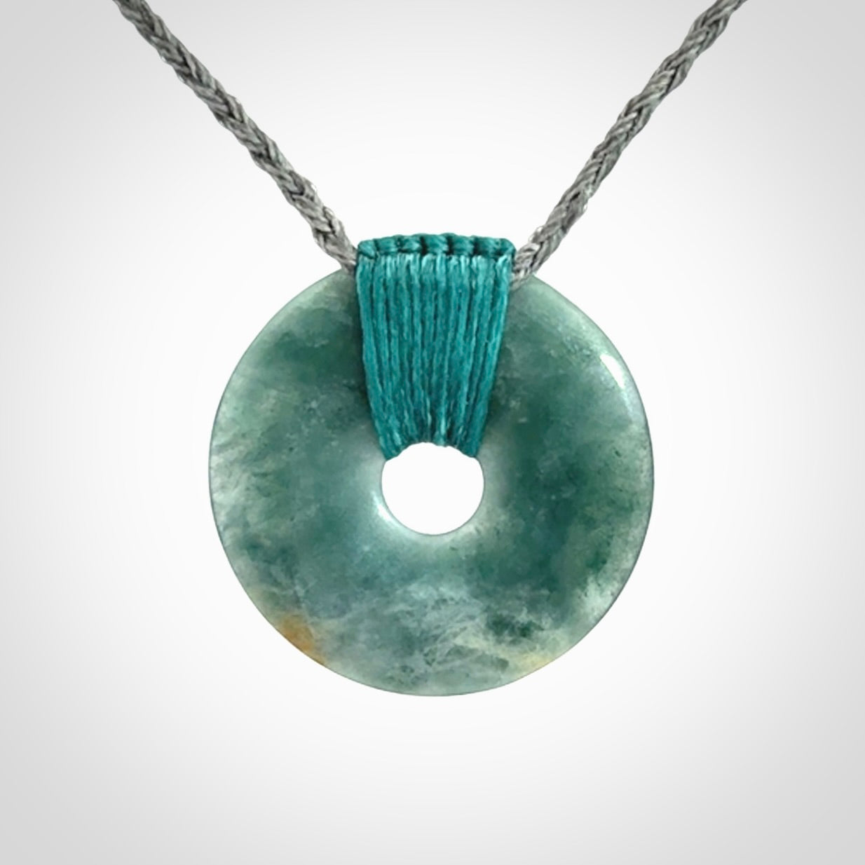 This is a hand carved disc pendant. Graeme carved this from Guatemalan Jadeite. It is a gorgeous blue colour and is an artistic piece of jewellery. Hand made by Graeme Wylie and delivered to you in a kete pouch.