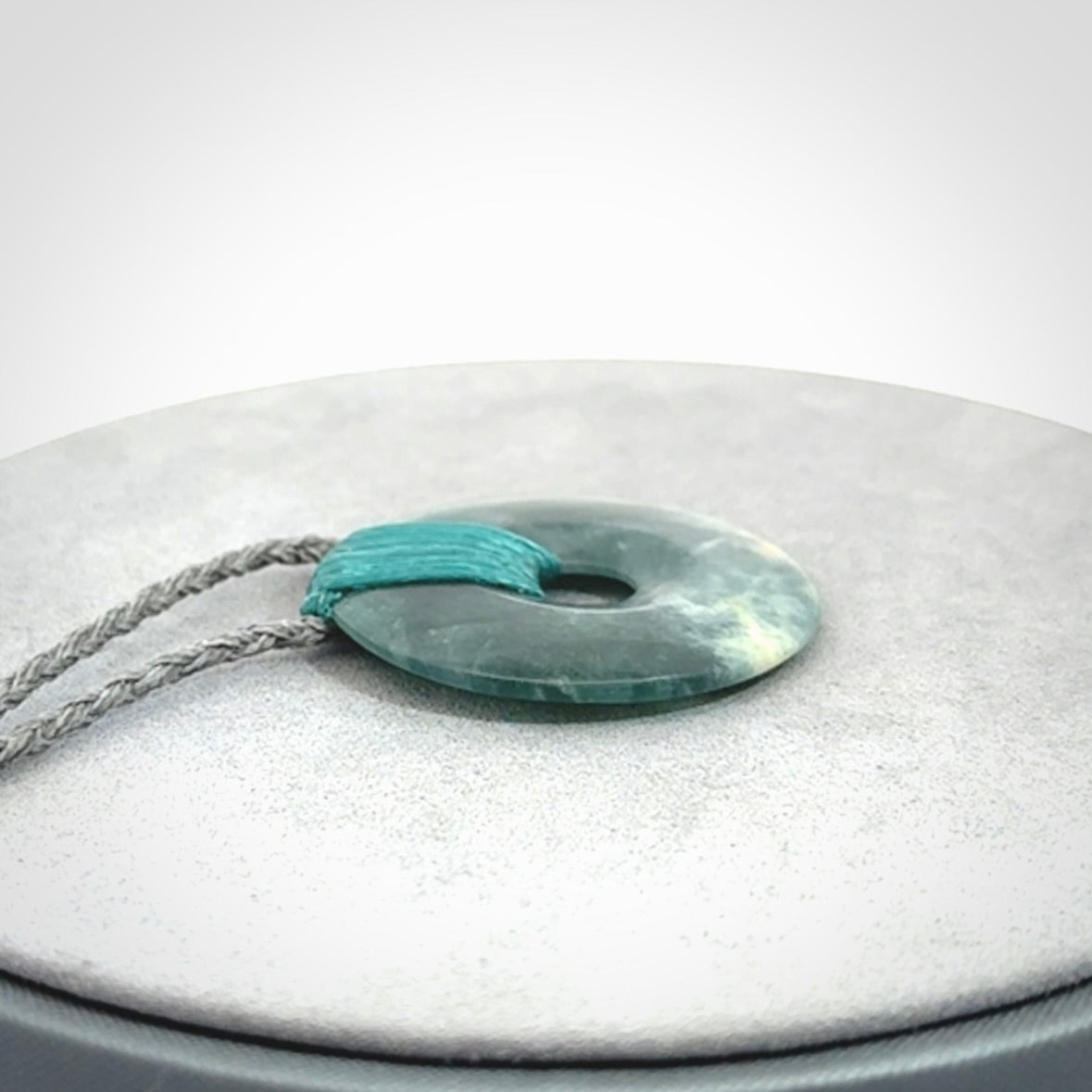 This is a hand carved disc pendant. Graeme carved this from Guatemalan Jadeite. It is a gorgeous blue colour and is an artistic piece of jewellery. Hand made by Graeme Wylie and delivered to you in a kete pouch.