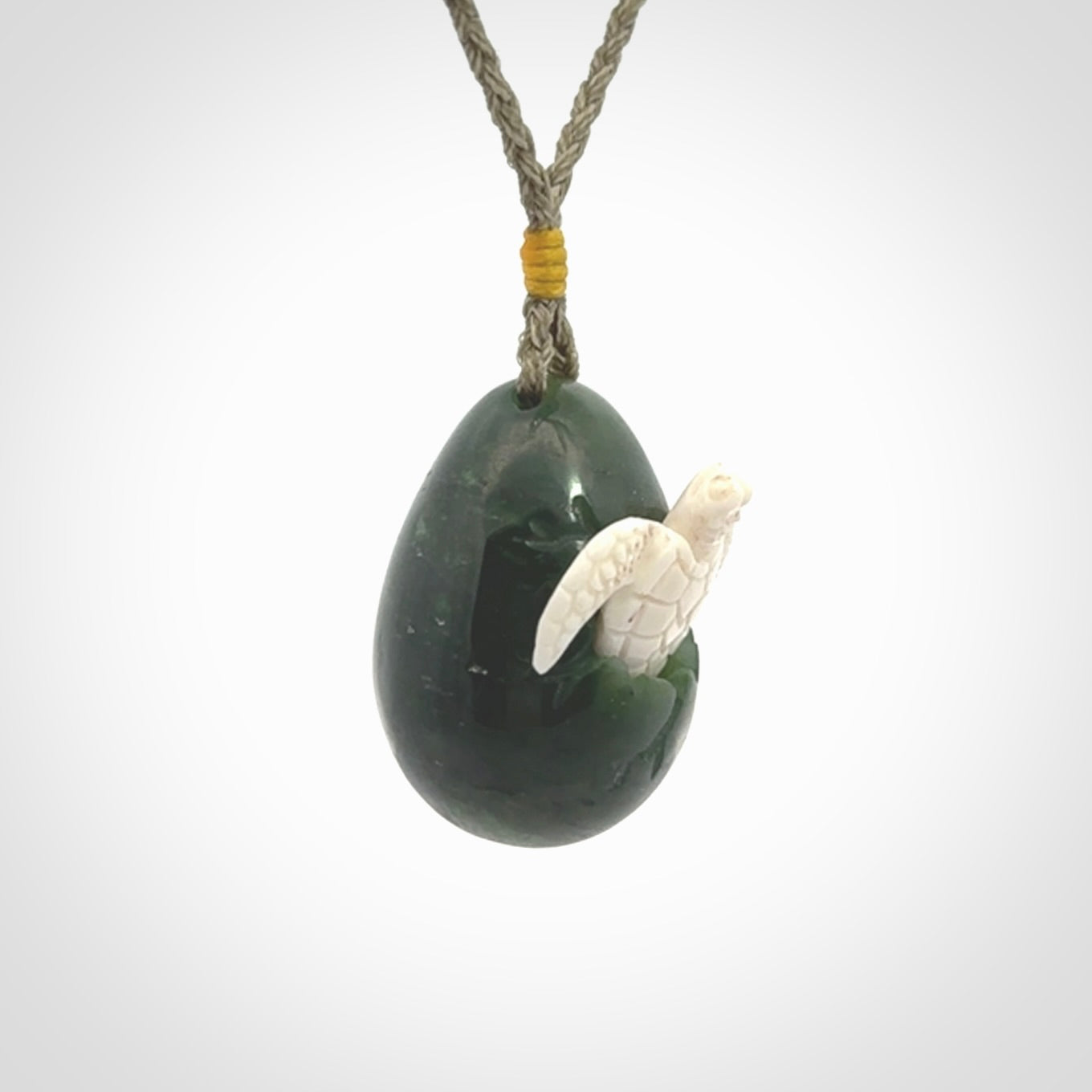 Hand carved turtle hatchling pendant. The egg is carved from green British Columbian jade and the turtle from bone. Designed and carved by NZ Pacific and for sale online.