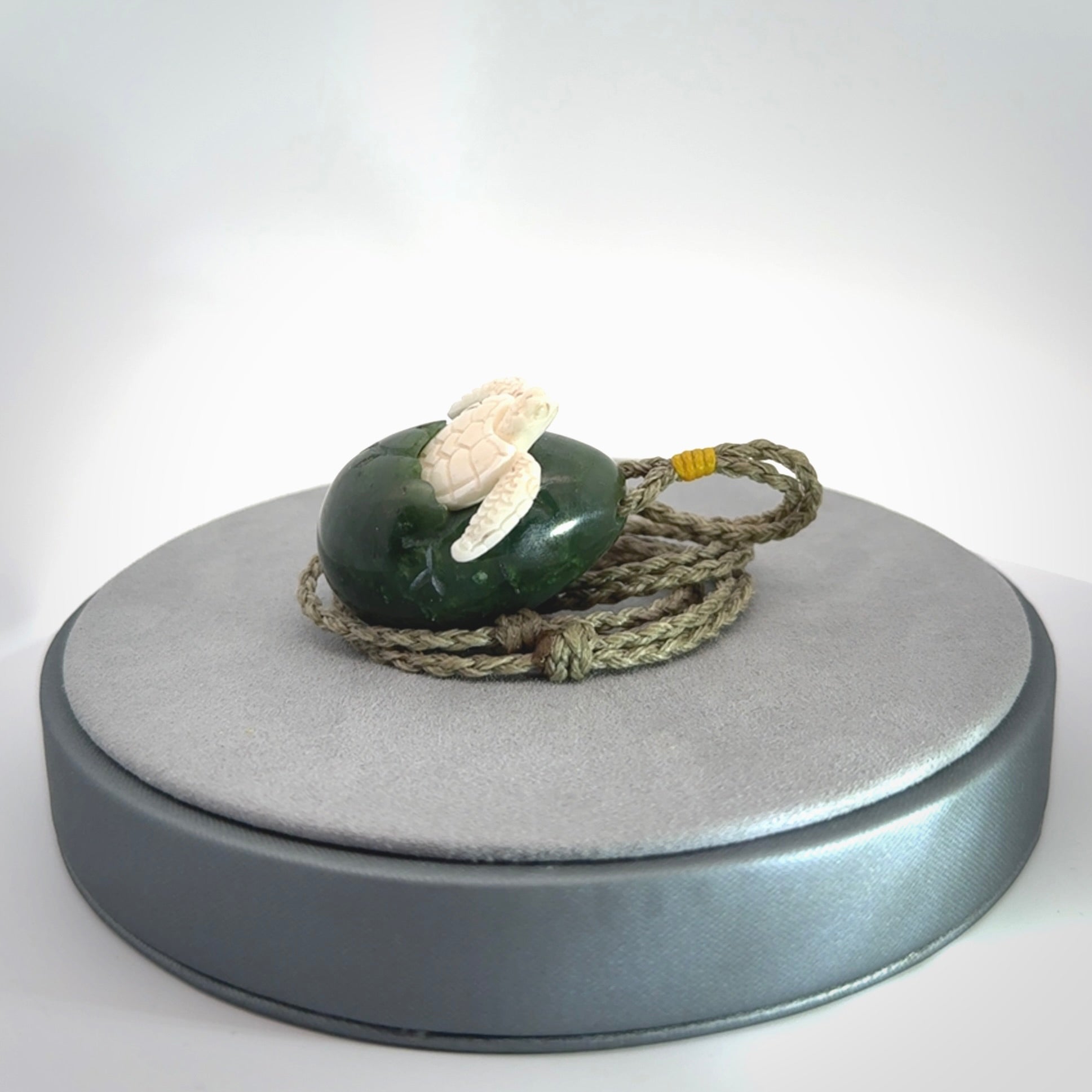 Hand carved turtle hatchling pendant. The egg is carved from green British Columbian jade and the turtle from bone. Designed and carved by NZ Pacific and for sale online.