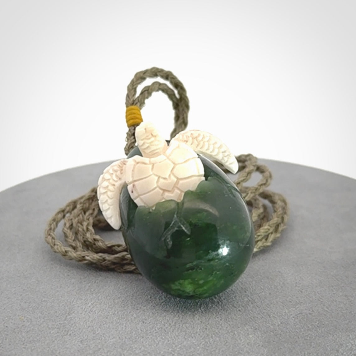 Hand carved turtle hatchling pendant. The egg is carved from green British Columbian jade and the turtle from bone. Designed and carved by NZ Pacific and for sale online.