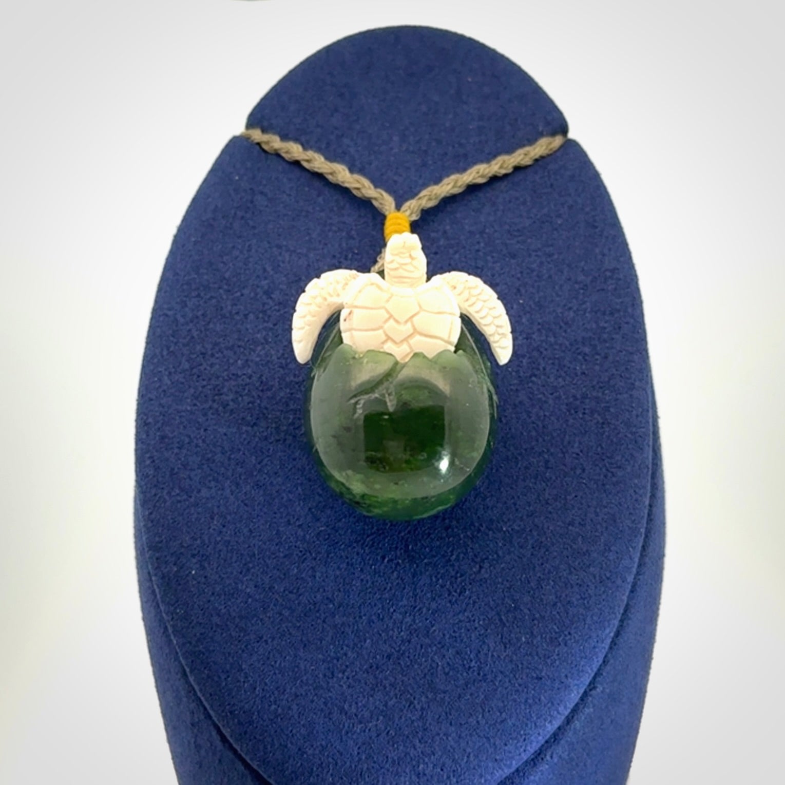 Hand carved turtle hatchling pendant. The egg is carved from green British Columbian jade and the turtle from bone. Designed and carved by NZ Pacific and for sale online.