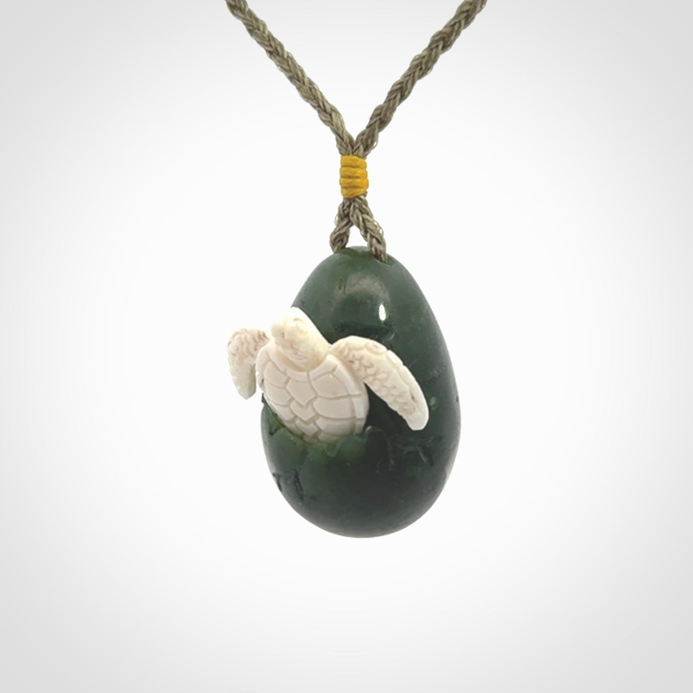 Hand carved turtle hatchling pendant. The egg is carved from green British Columbian jade and the turtle from bone. Designed and carved by NZ Pacific and for sale online.