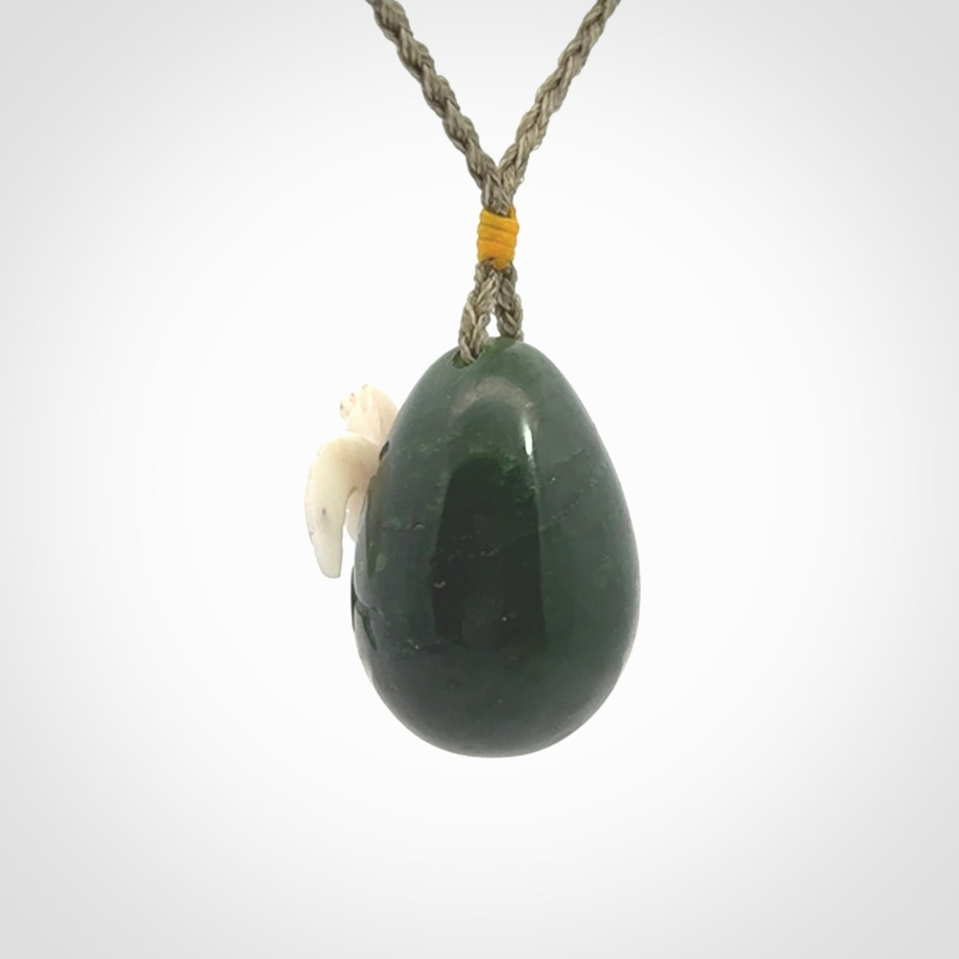 Hand carved turtle hatchling pendant. The egg is carved from green British Columbian jade and the turtle from bone. Designed and carved by NZ Pacific and for sale online.