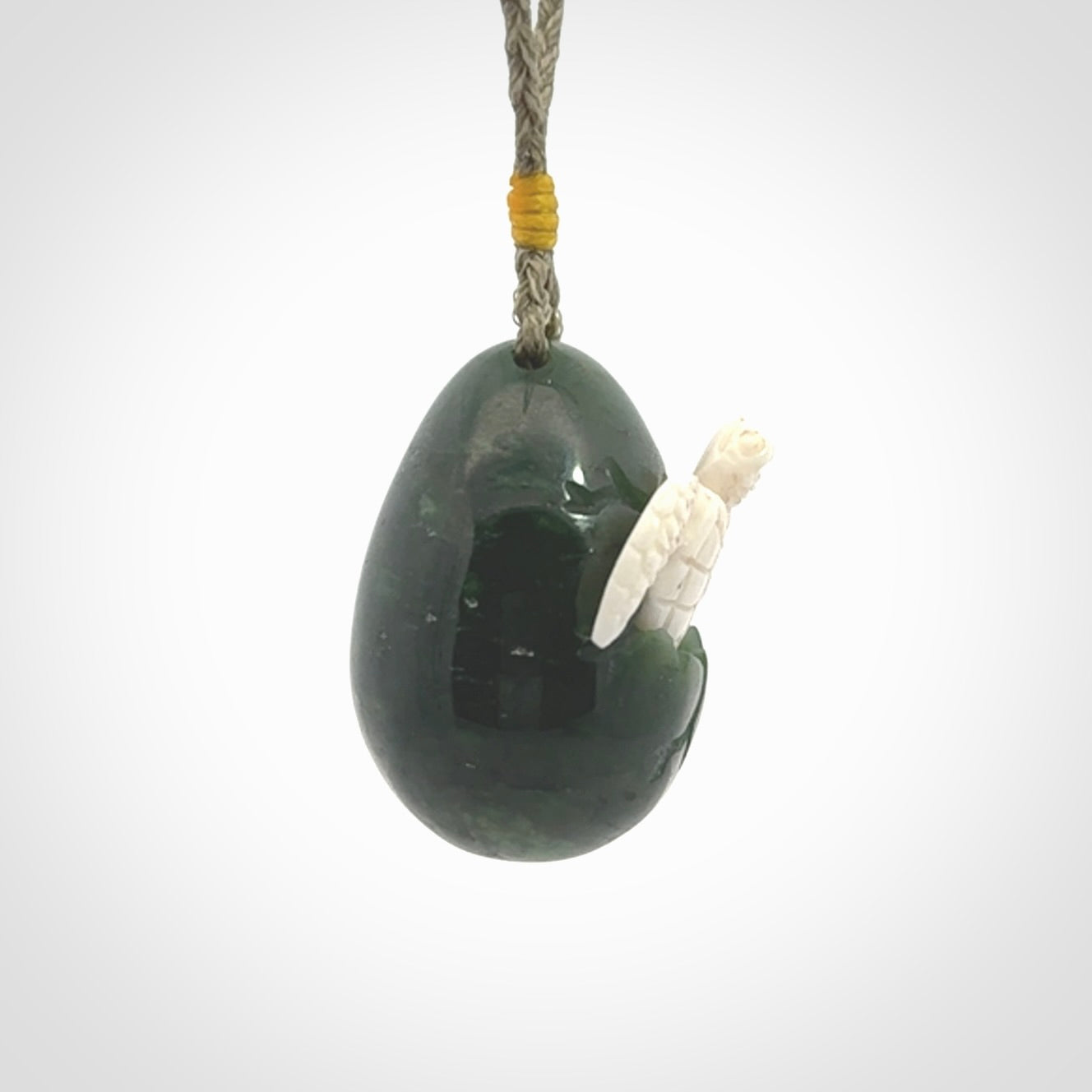 Hand carved turtle hatchling pendant. The egg is carved from green British Columbian jade and the turtle from bone. Designed and carved by NZ Pacific and for sale online.