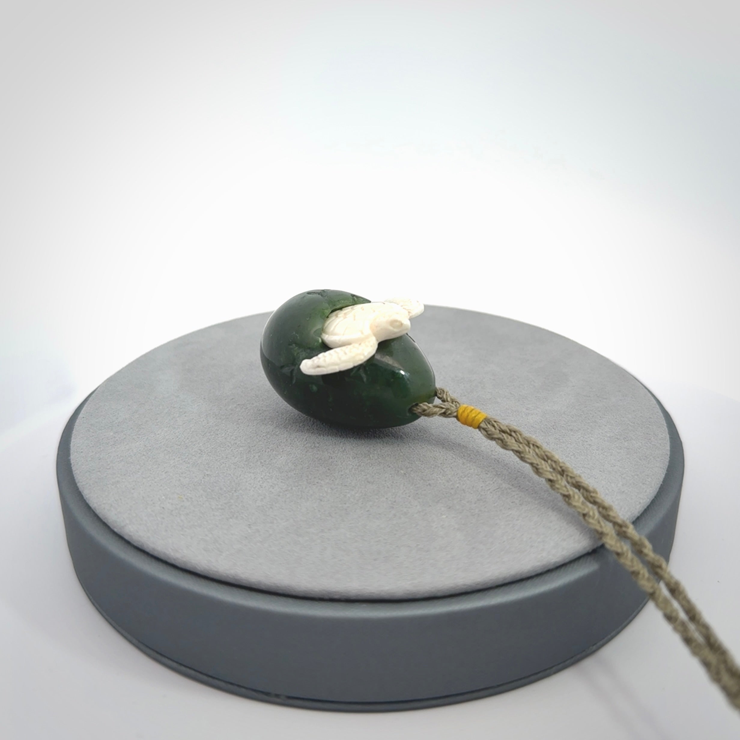 Hand carved turtle hatchling pendant. The egg is carved from green British Columbian jade and the turtle from bone. Designed and carved by NZ Pacific and for sale online.