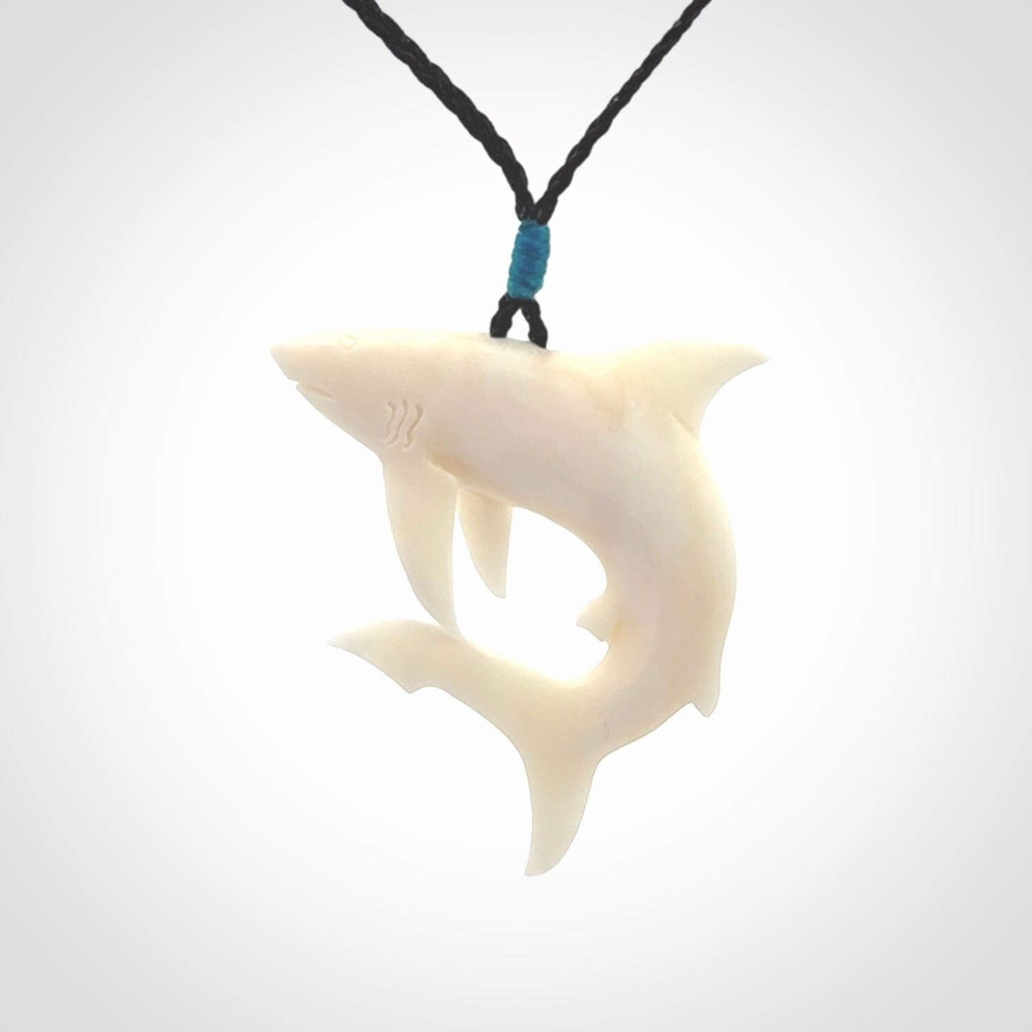 This photo shows a bone shark pendant hand carved in bone. It is provided with an adjustable cord.