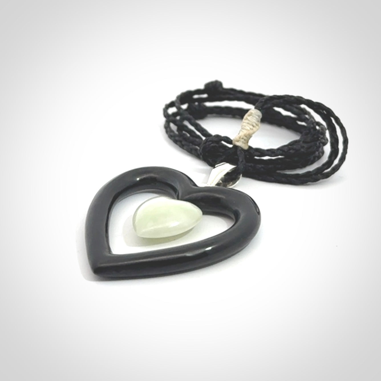 Black Jade Heart pendant with Jadeite heart centre. Hand carved for NZ Pacific. Handmade jewellery for sale online. The cord is a 3-braid plait in black and is adjustable. Double heart necklace for men and women. Heart necklace hand made from black jade stone and Jadeite.
