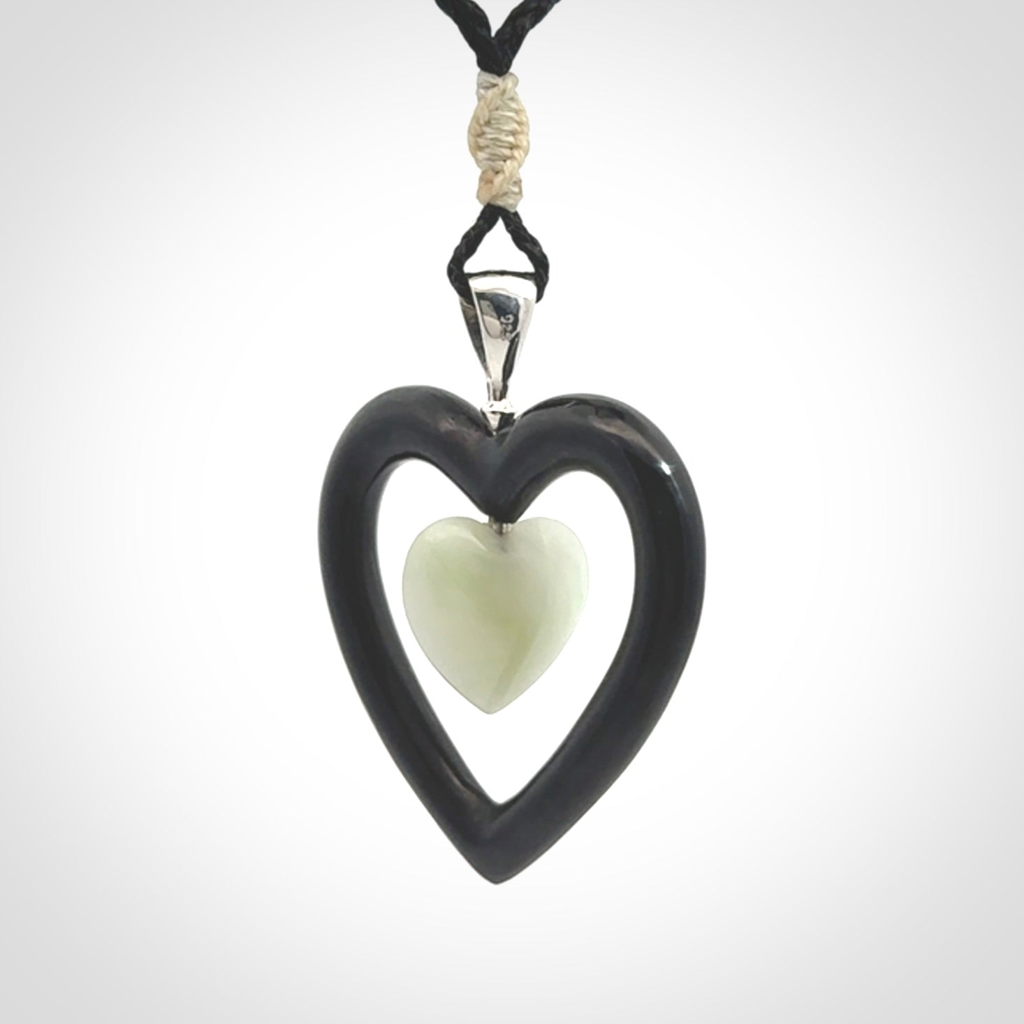 Black Jade Heart pendant with Jadeite heart centre. Hand carved for NZ Pacific. Handmade jewellery for sale online. The cord is a 3-braid plait in black and is adjustable. Double heart necklace for men and women. Heart necklace hand made from black jade stone and Jadeite.