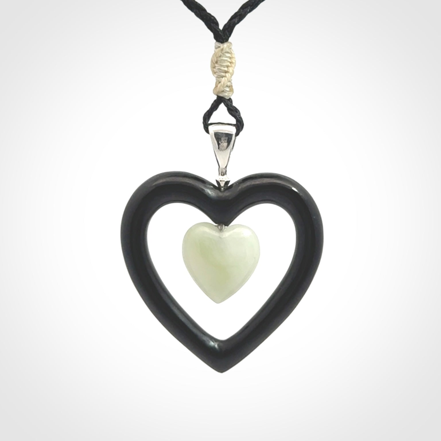 Black Jade Heart pendant with Jadeite heart centre. Hand carved for NZ Pacific. Handmade jewellery for sale online. The cord is a 3-braid plait in black and is adjustable. Double heart necklace for men and women. Heart necklace hand made from black jade stone and Jadeite.