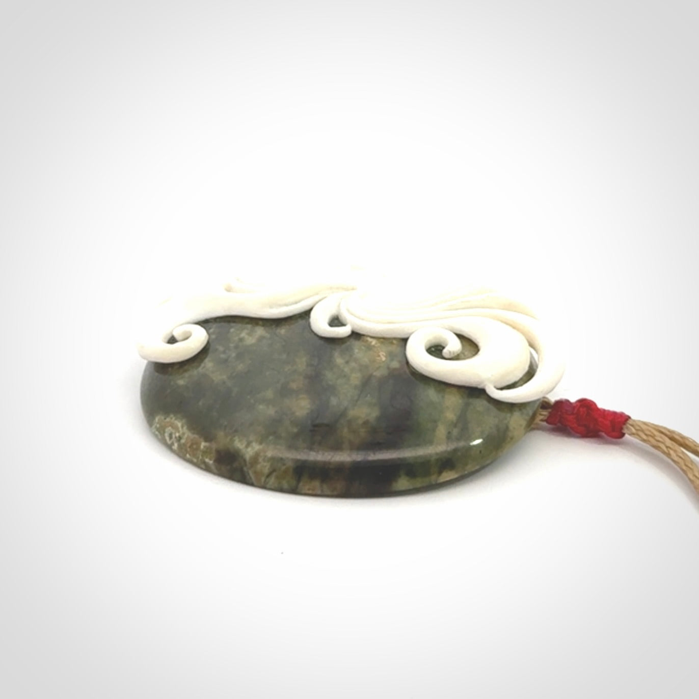 A Jade pendant with bone face. Hand carved Jade and Bone art to wear. One only.
