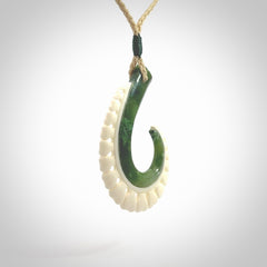 This photo shows a beautiful jade hook with bone pendant. It is handcarved from a piece of mottled green Jade, with fascinating mauve tinges through the stone. We have this on a adjustable cord. We ship this worldwide with an express courier service. Postage is free.
