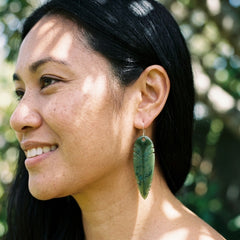 Woman wearing kaka feather jade earrings