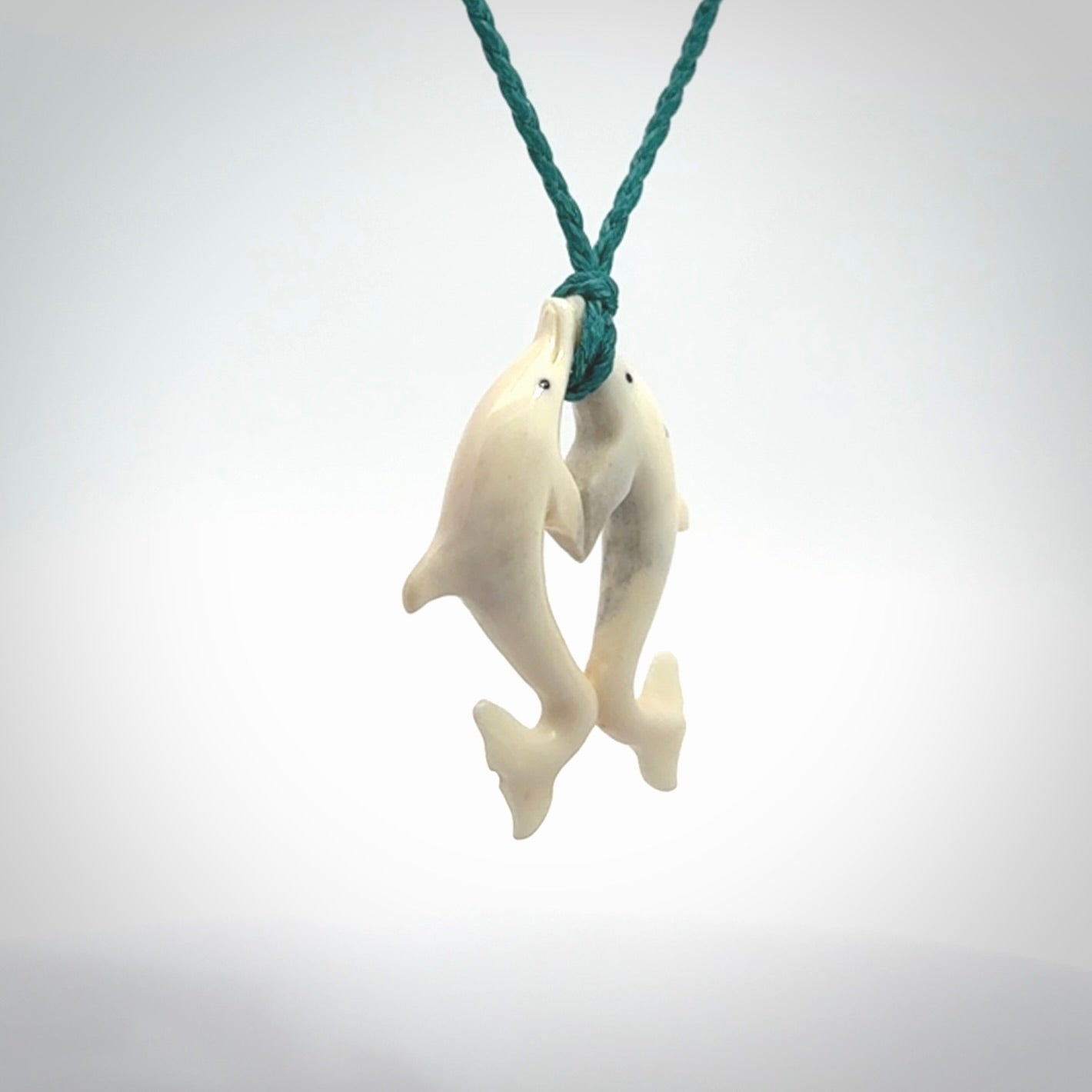 Hand carved natural double dolphin bone pendant. Hand made bone dolphin necklace, delivered with Express Courier. Hand crafted bone double dolphin pendant. Provided with an adjustable blue cord.