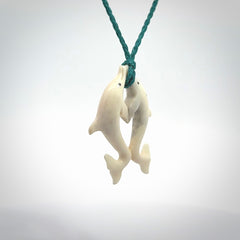 Hand carved natural double dolphin bone pendant. Hand made bone dolphin necklace, delivered with Express Courier. Hand crafted bone double dolphin pendant. Provided with an adjustable blue cord.