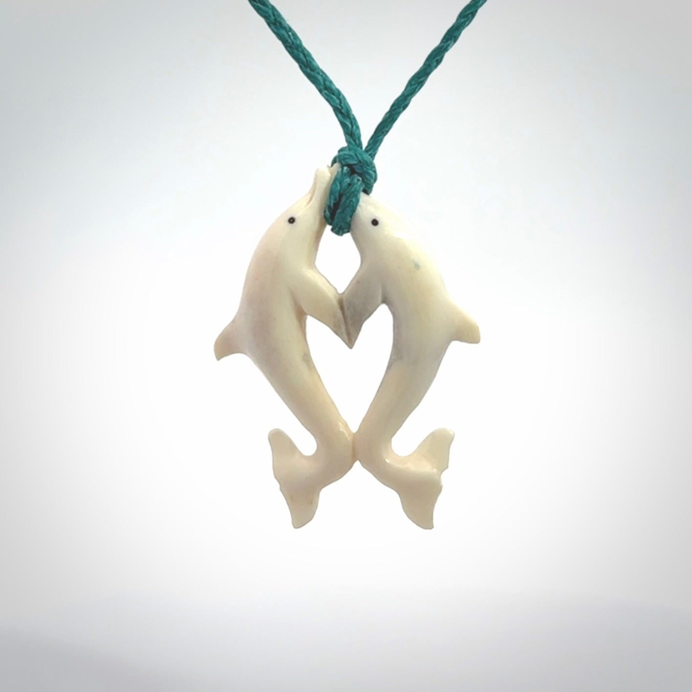 Hand carved natural double dolphin bone pendant. Hand made bone dolphin necklace, delivered with Express Courier. Hand crafted bone double dolphin pendant. Provided with an adjustable blue cord.