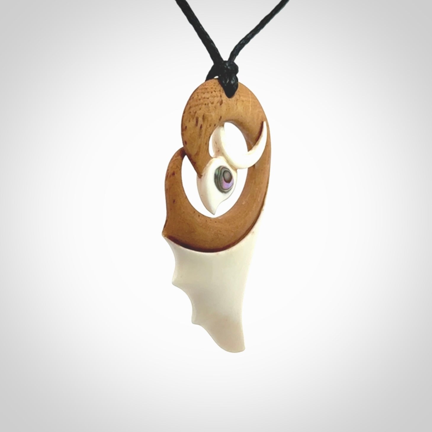 A hand carved bone contemporary bird pendant. The cord is a black colour and is a fixed length. A medium sized hand made contemporary necklace by New Zealand artist Kerry Thompson. Kerry has stained parts of the bone which really add to the dimension of this pendant. One off work of art to wear.