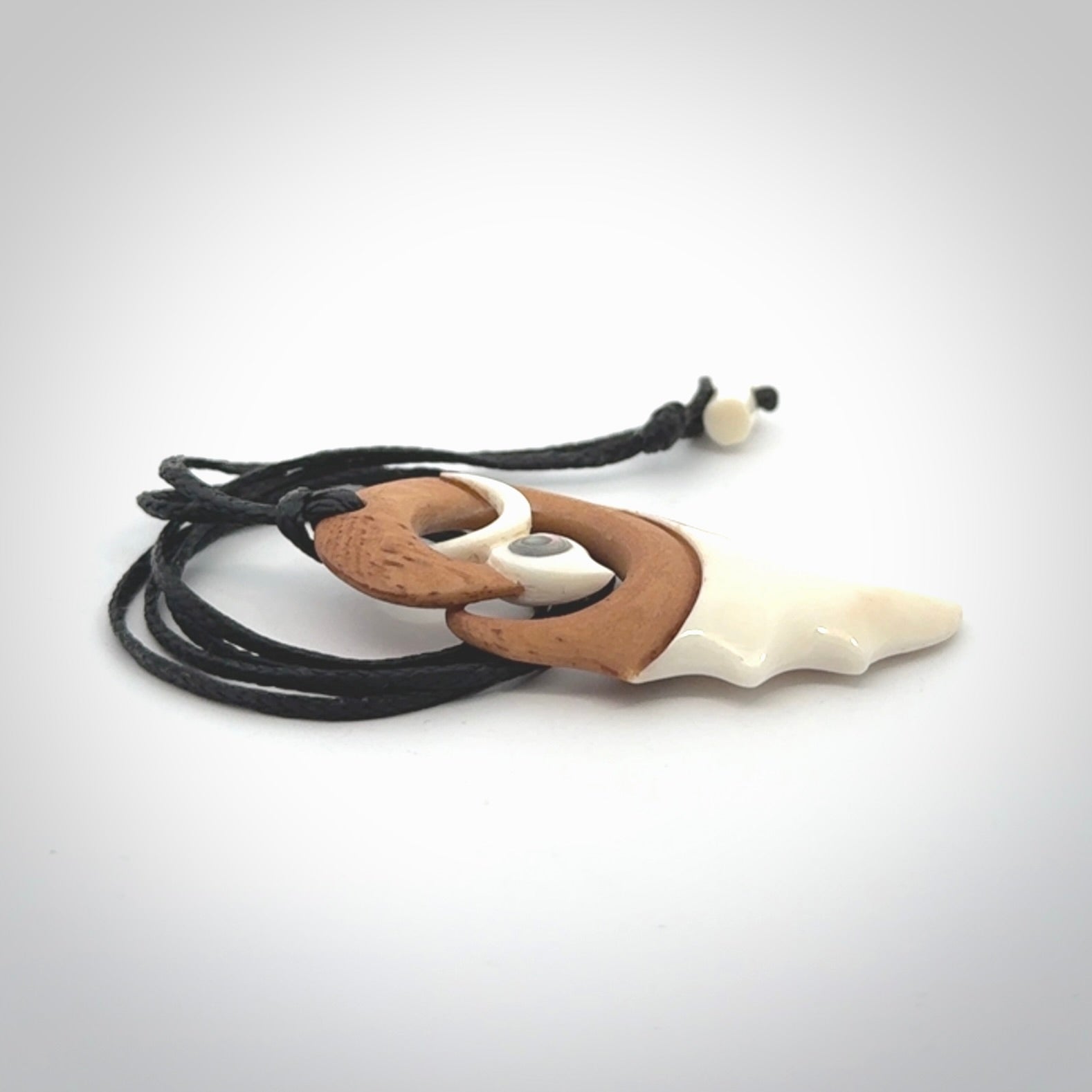 A hand carved bone contemporary bird pendant. The cord is a black colour and is a fixed length. A medium sized hand made contemporary necklace by New Zealand artist Kerry Thompson. Kerry has stained parts of the bone which really add to the dimension of this pendant. One off work of art to wear.