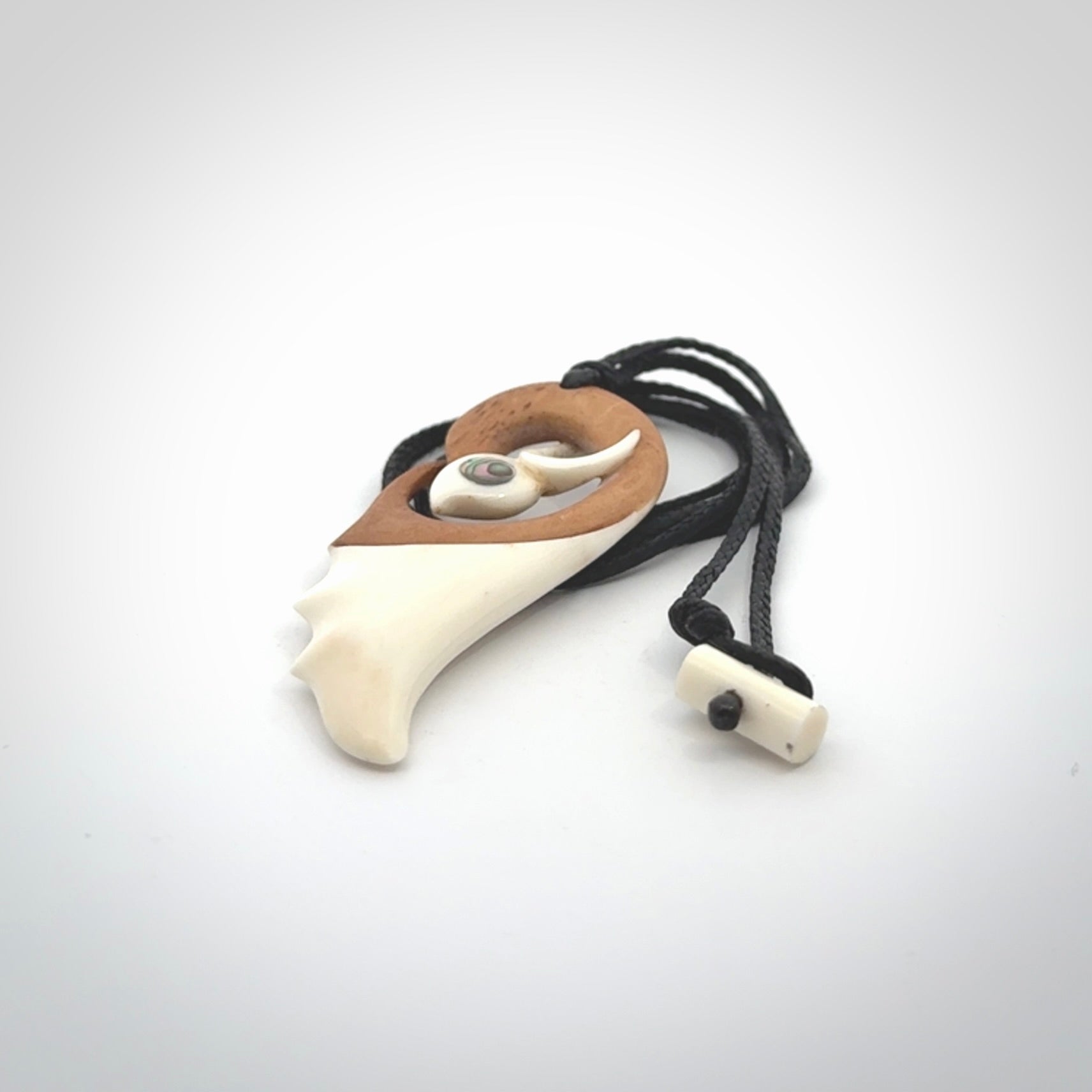 A hand carved bone contemporary bird pendant. The cord is a black colour and is a fixed length. A medium sized hand made contemporary necklace by New Zealand artist Kerry Thompson. Kerry has stained parts of the bone which really add to the dimension of this pendant. One off work of art to wear.
