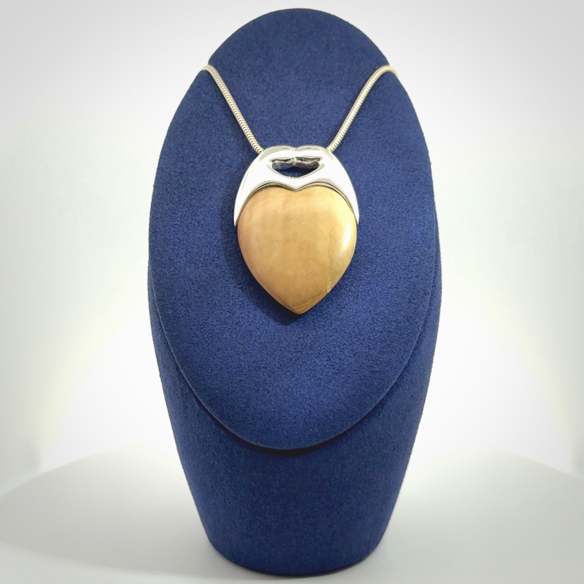 This picture shows a pendant that we have carved in a combination of sterling silver and woolly mammoth. It shows a symbolic kiss, with two heads coming together and both embracing a woolly mammoth heart. The necklace is a sterling silver chain.