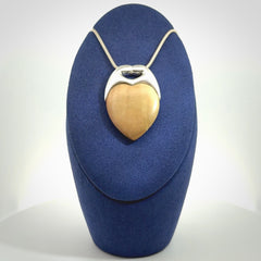 This picture shows a pendant that we have carved in a combination of sterling silver and woolly mammoth. It shows a symbolic kiss, with two heads coming together and both embracing a woolly mammoth heart. The necklace is a sterling silver chain.