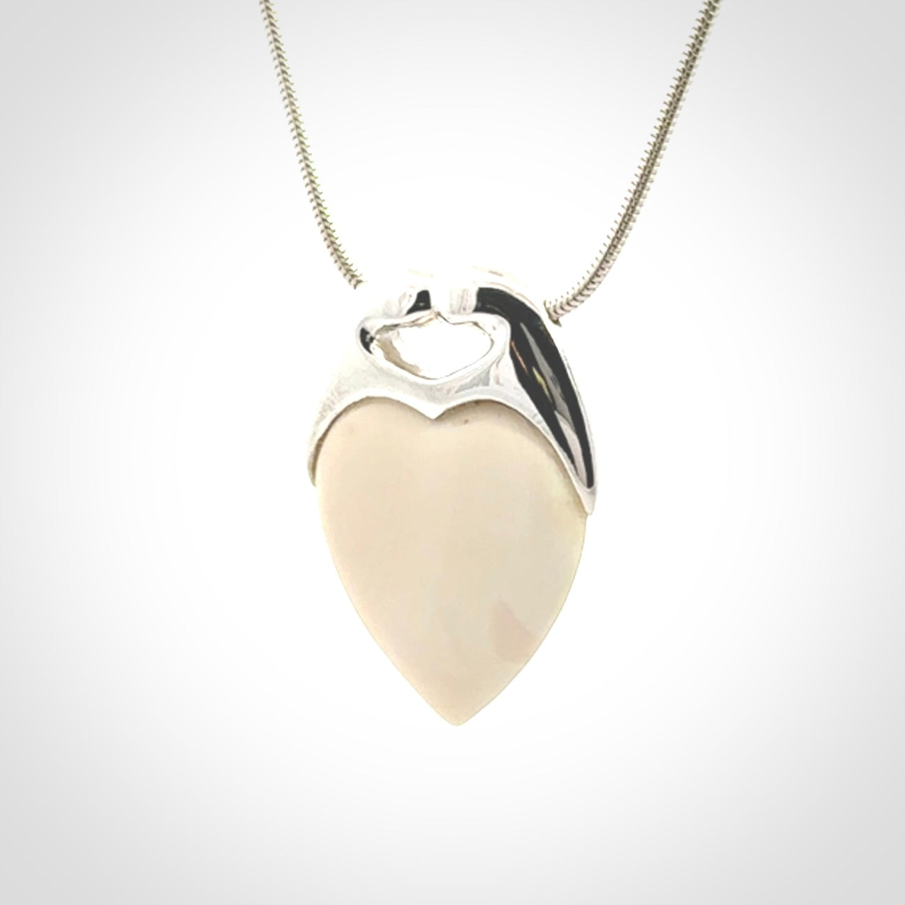 This picture shows a pendant that we have carved in a combination of sterling silver and woolly mammoth. It shows a symbolic kiss, with two heads coming together and both embracing a woolly mammoth heart. The necklace is a sterling silver chain.