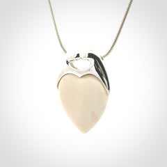 This picture shows a pendant that we have carved in a combination of sterling silver and woolly mammoth. It shows a symbolic kiss, with two heads coming together and both embracing a woolly mammoth heart. The necklace is a sterling silver chain.