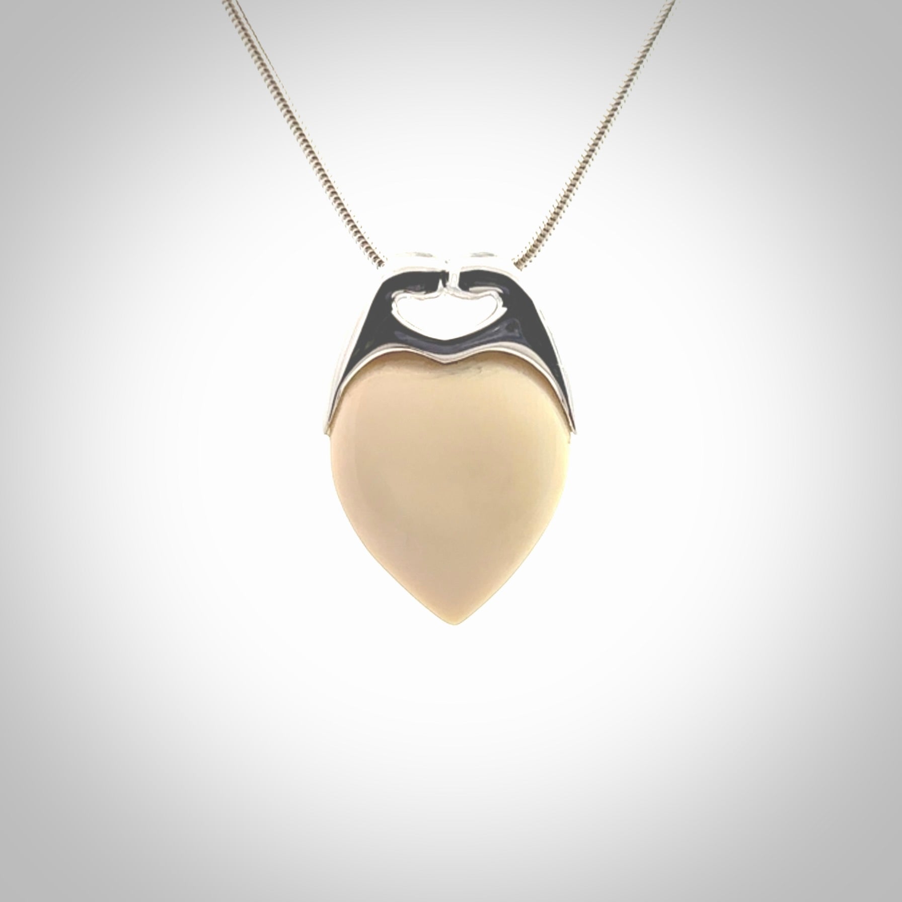 This picture shows a pendant that we have carved in a combination of sterling silver and woolly mammoth. It shows a symbolic kiss, with two heads coming together and both embracing a woolly mammoth heart. The necklace is a sterling silver chain.