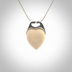 This picture shows a pendant that we have carved in a combination of sterling silver and woolly mammoth. It shows a symbolic kiss, with two heads coming together and both embracing a woolly mammoth heart. The necklace is a sterling silver chain.