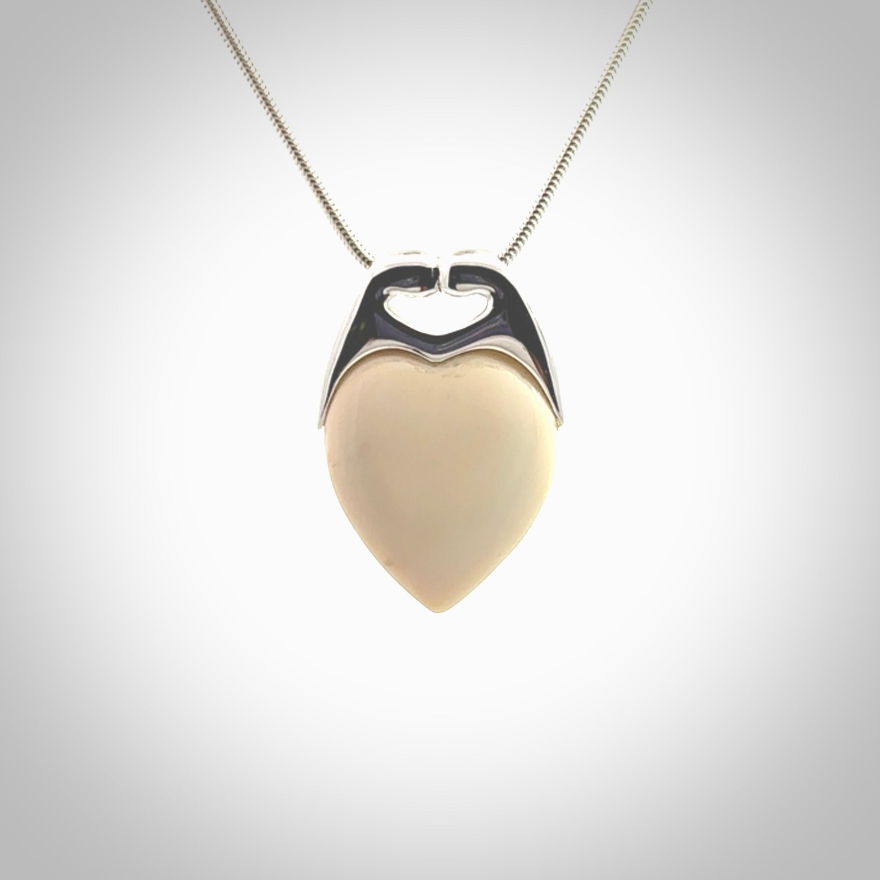 This picture shows a pendant that we have carved in a combination of sterling silver and woolly mammoth. It shows a symbolic kiss, with two heads coming together and both embracing a woolly mammoth heart. The necklace is a sterling silver chain.