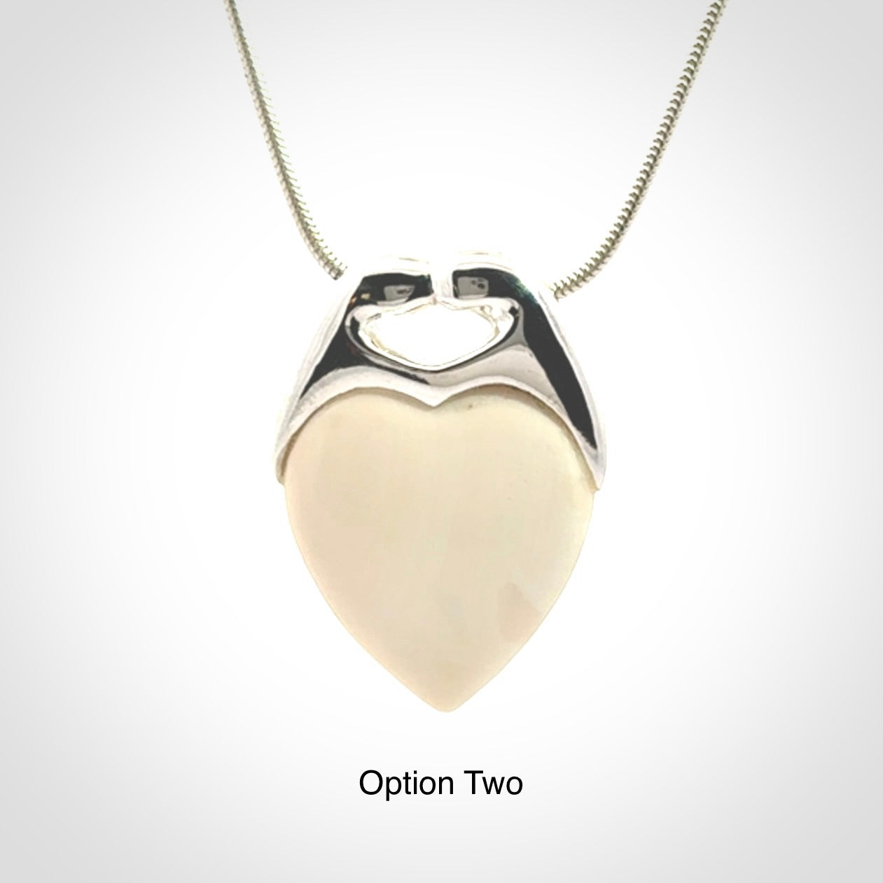 This picture shows a pendant that we have carved in a combination of sterling silver and woolly mammoth. It shows a symbolic kiss, with two heads coming together and both embracing a woolly mammoth heart. The necklace is a sterling silver chain.