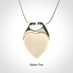 This picture shows a pendant that we have carved in a combination of sterling silver and woolly mammoth. It shows a symbolic kiss, with two heads coming together and both embracing a woolly mammoth heart. The necklace is a sterling silver chain.
