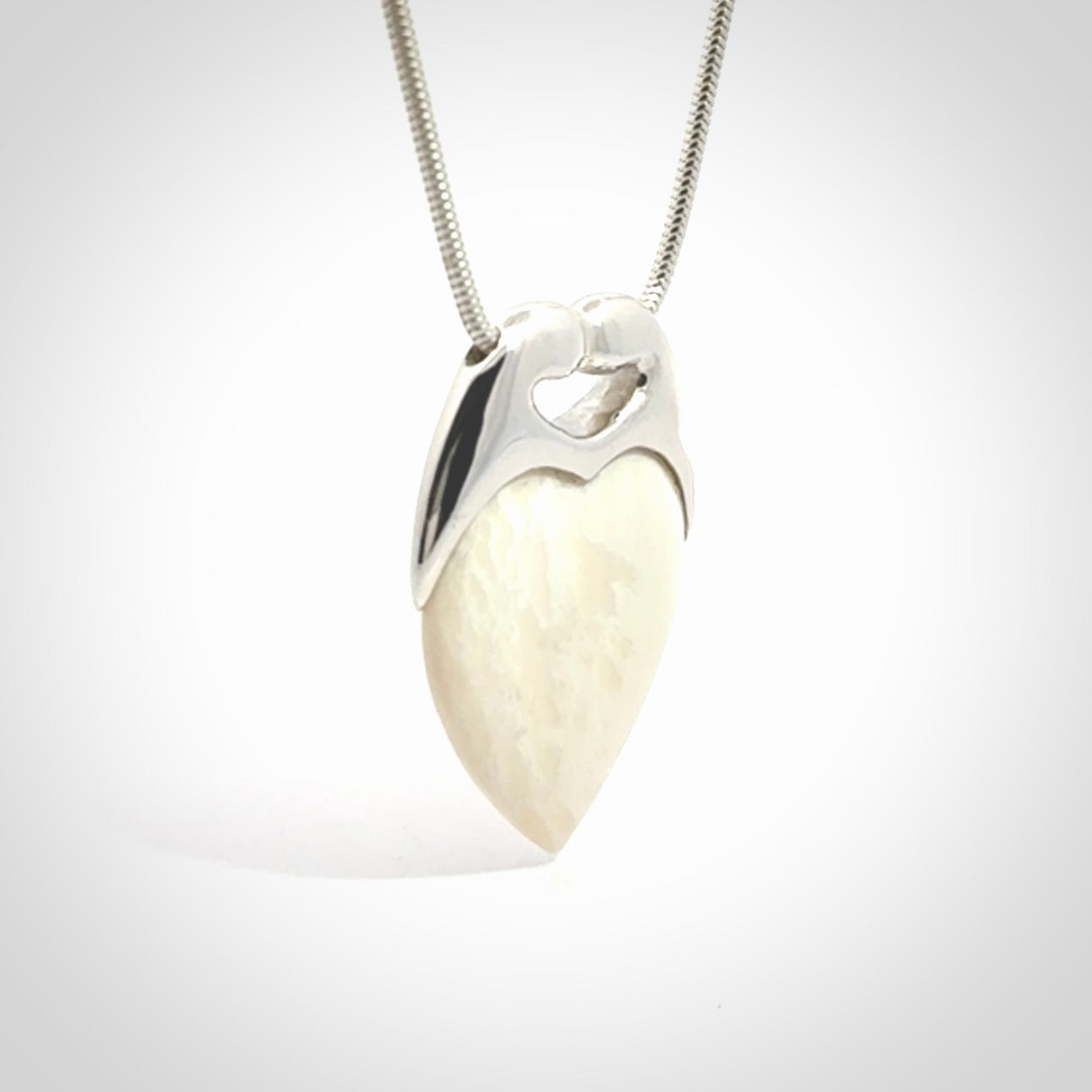 This picture shows a pendant that we have carved in a combination of sterling silver and woolly mammoth. It shows a symbolic kiss, with two heads coming together and both embracing a woolly mammoth heart. The necklace is a sterling silver chain.