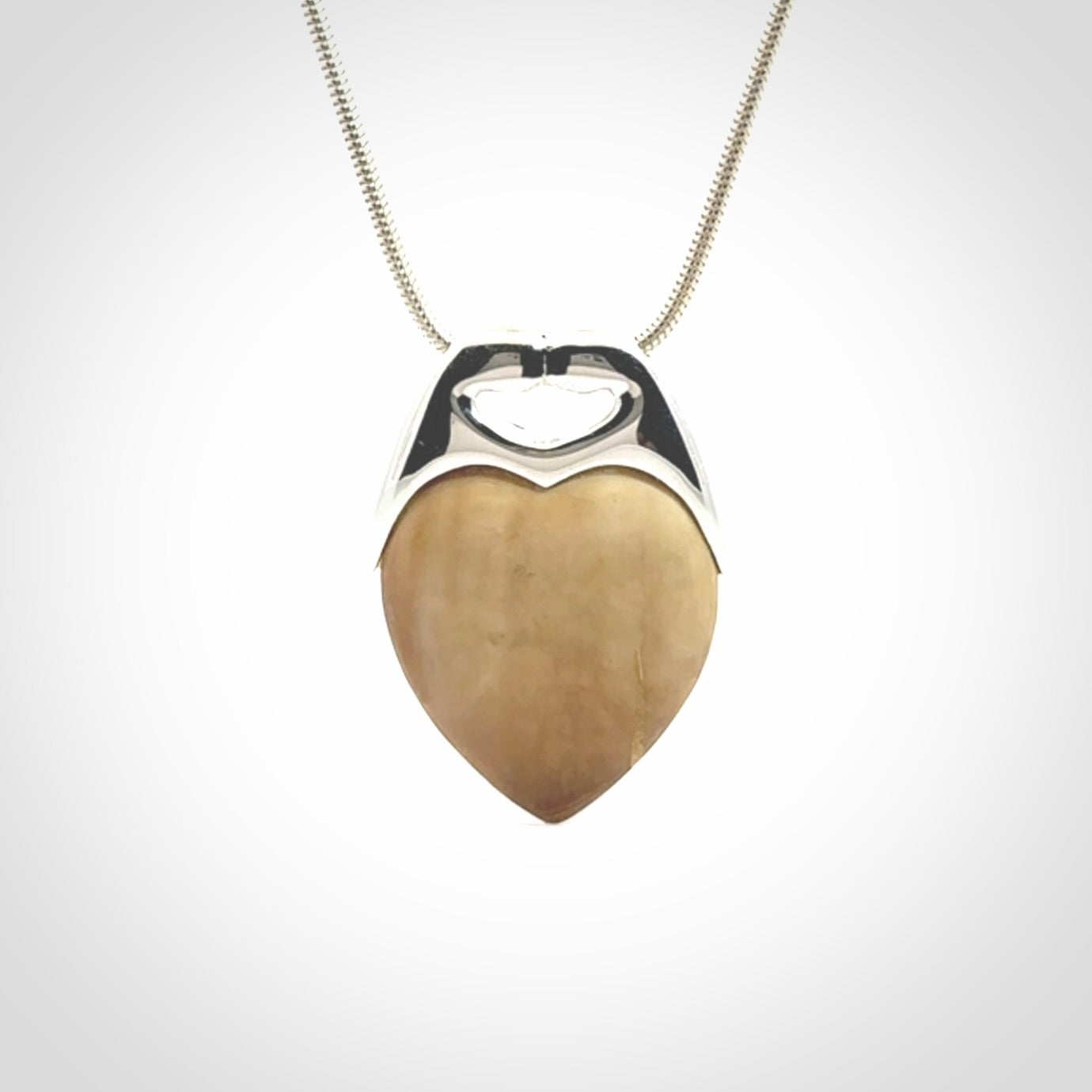 This picture shows a pendant that we have carved in a combination of sterling silver and woolly mammoth. It shows a symbolic kiss, with two heads coming together and both embracing a woolly mammoth heart. The necklace is a sterling silver chain.