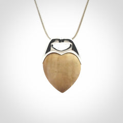 This picture shows a pendant that we have carved in a combination of sterling silver and woolly mammoth. It shows a symbolic kiss, with two heads coming together and both embracing a woolly mammoth heart. The necklace is a sterling silver chain.