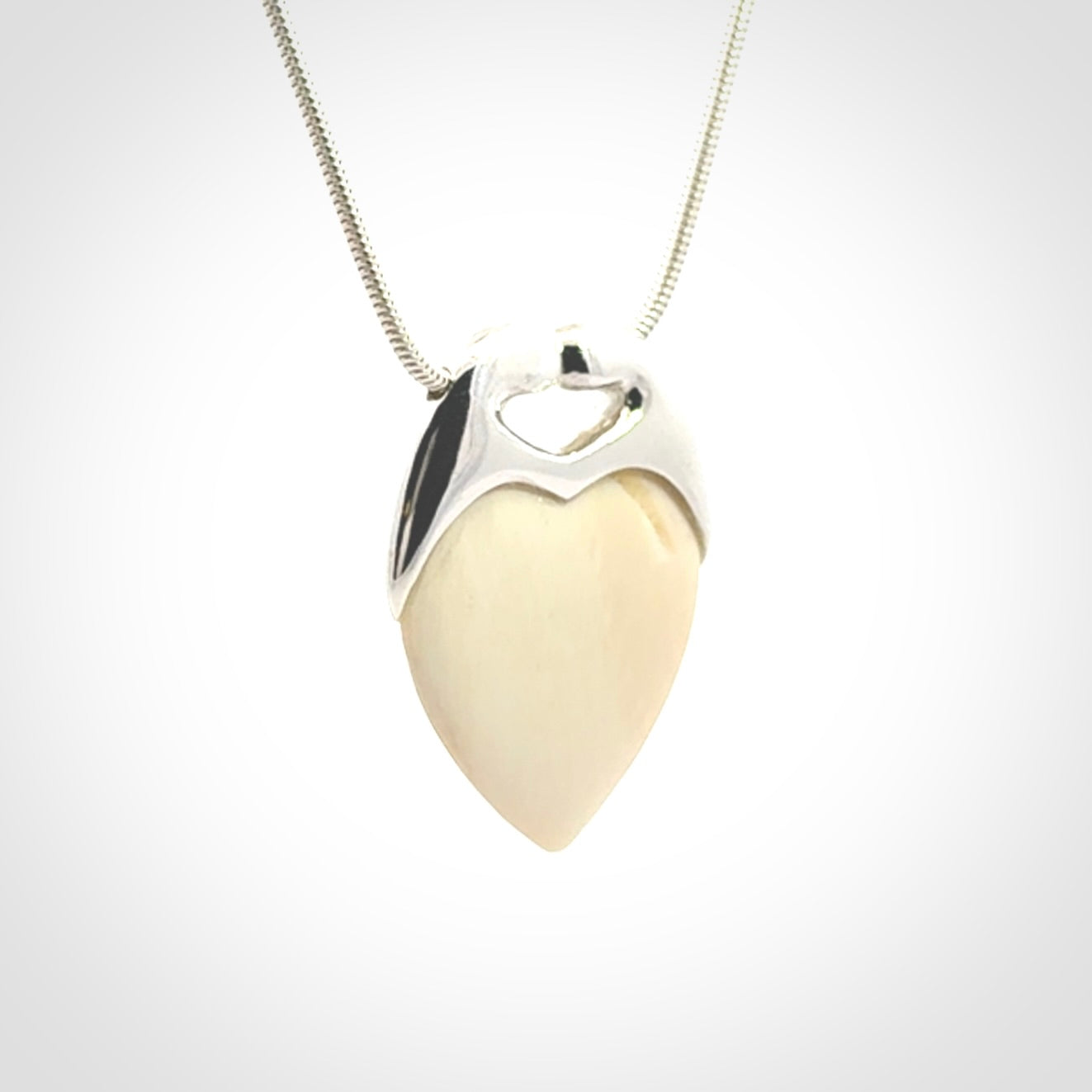 This picture shows a pendant that we have carved in a combination of sterling silver and woolly mammoth. It shows a symbolic kiss, with two heads coming together and both embracing a woolly mammoth heart. The necklace is a sterling silver chain.