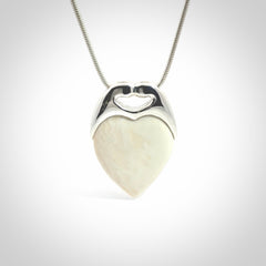 This picture shows a pendant that we have carved in a combination of sterling silver and woolly mammoth. It shows a symbolic kiss, with two heads coming together and both embracing a woolly mammoth heart. The necklace is a sterling silver chain.